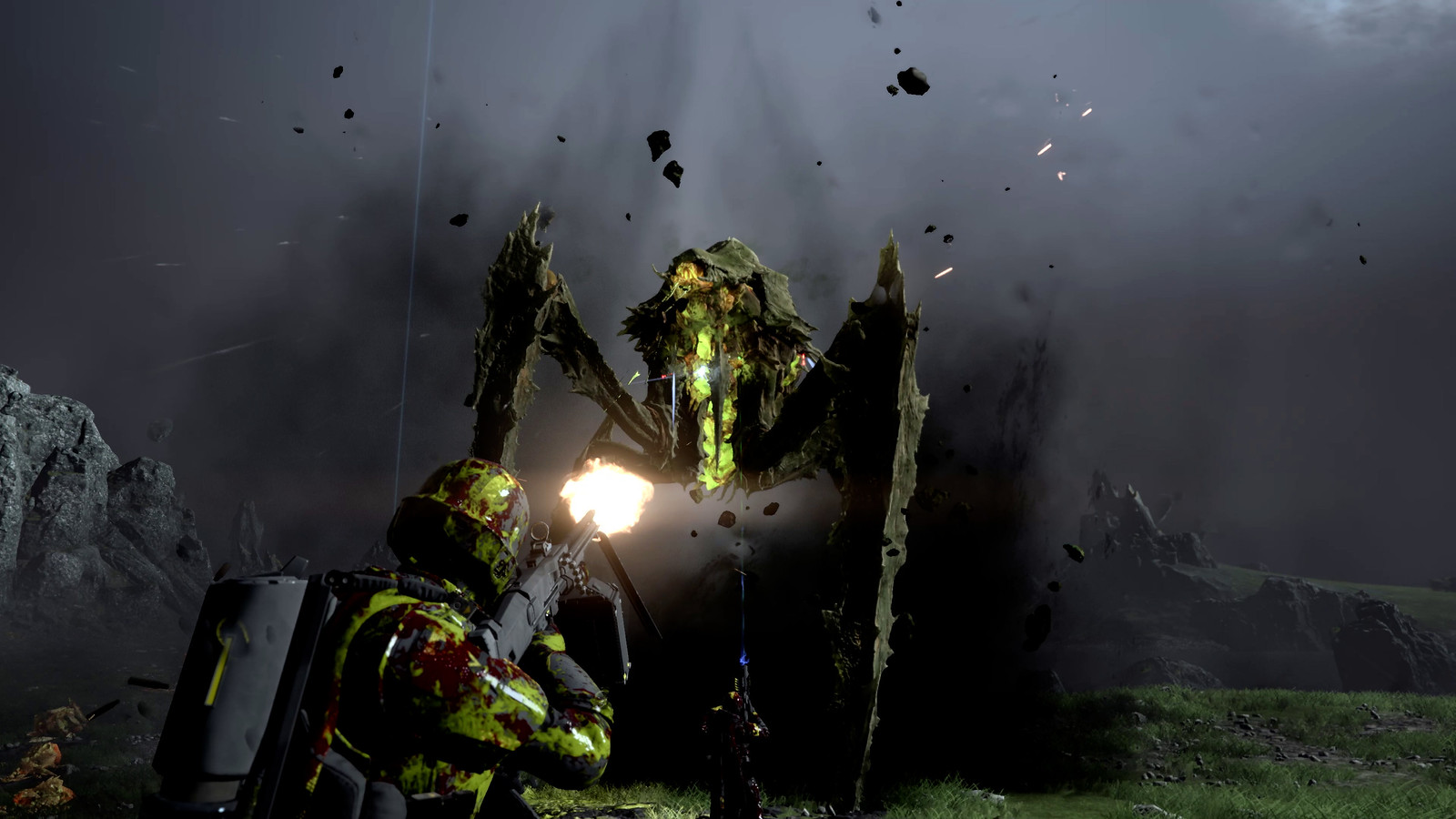 A soldier in futuristic armour coated in yellow and green alien blood shoots up at a staggeringly tall behemoth.