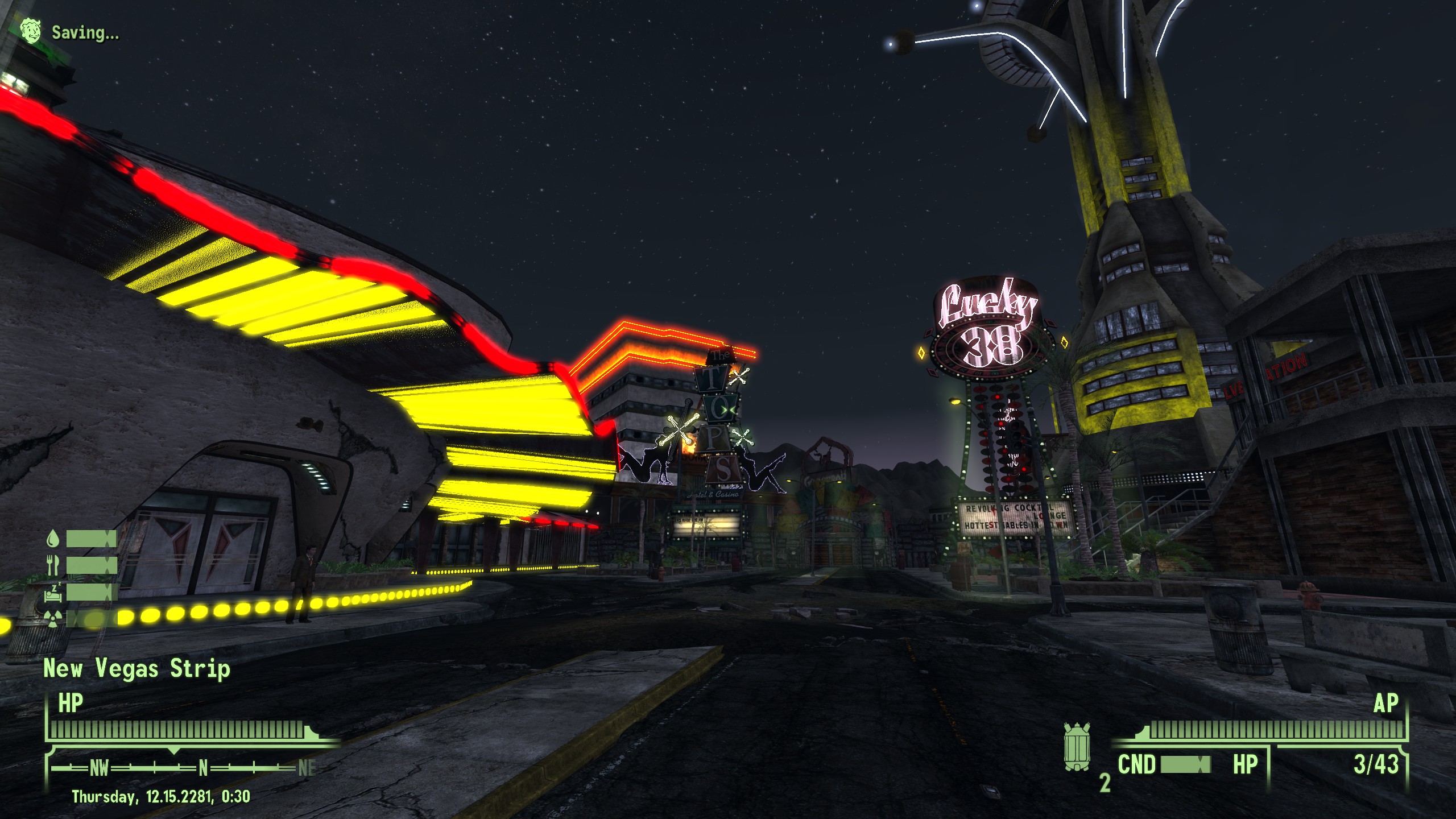 The New Vegas Strip from Fallout New Vegas. Neon signs and lights flash against a night sky with towers in the background reaching into the sky. A two lane road stretches between the two ends of the strip.